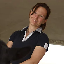 Juliane Grube lächelnd auf einem Rappen mit weißer Schabracke